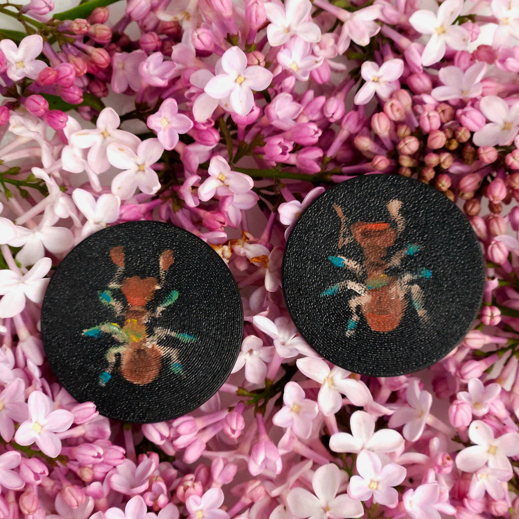 Pair of earrings with insect design on a bed of pink flowers