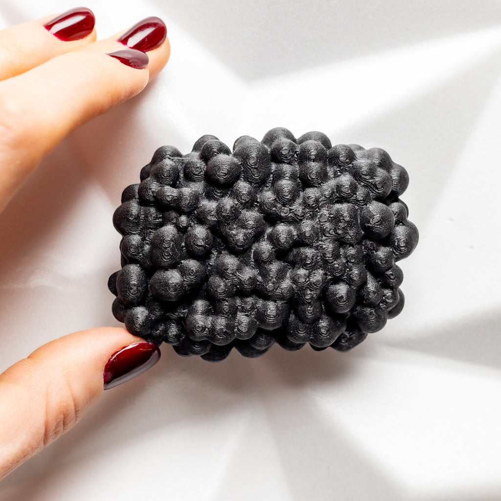Black textured brooch - bunch of berries held by a hand  on a white background