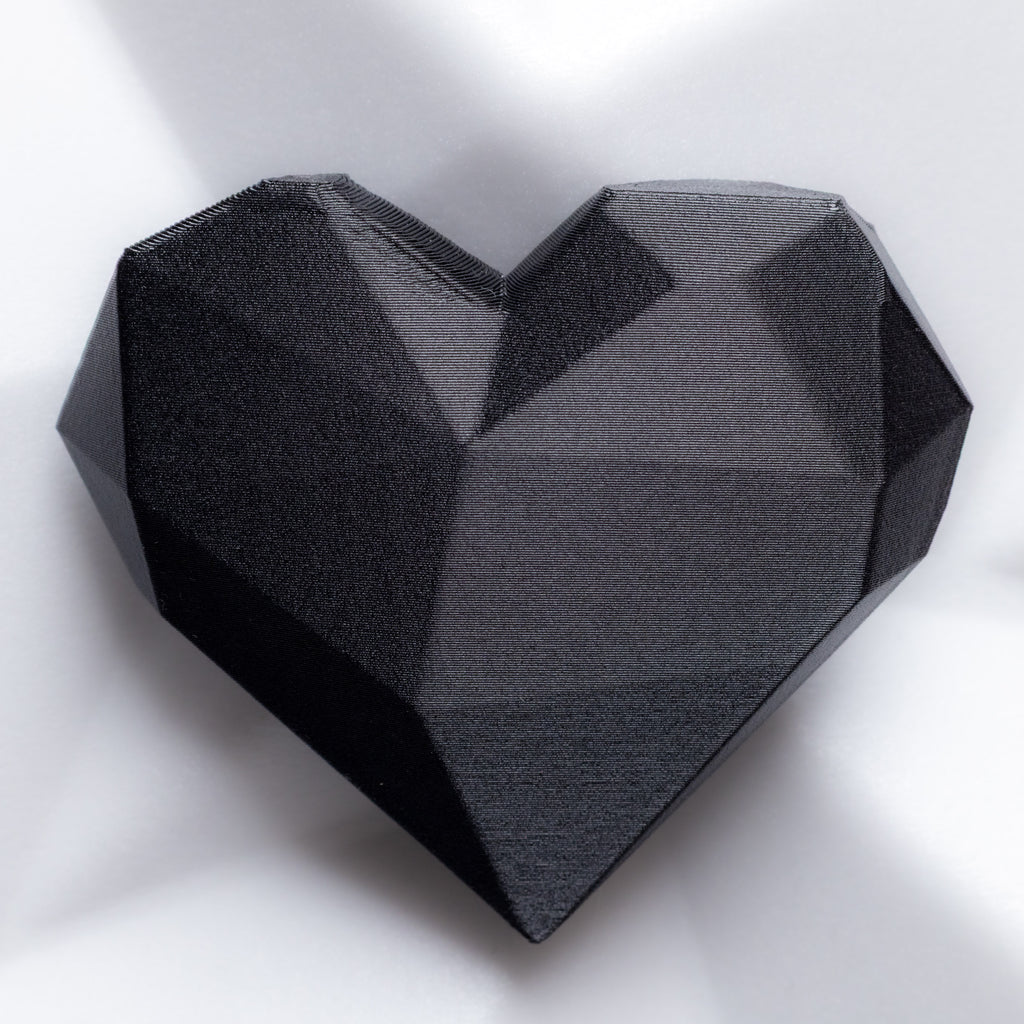 Black geometric heart-shaped brooch on a white background