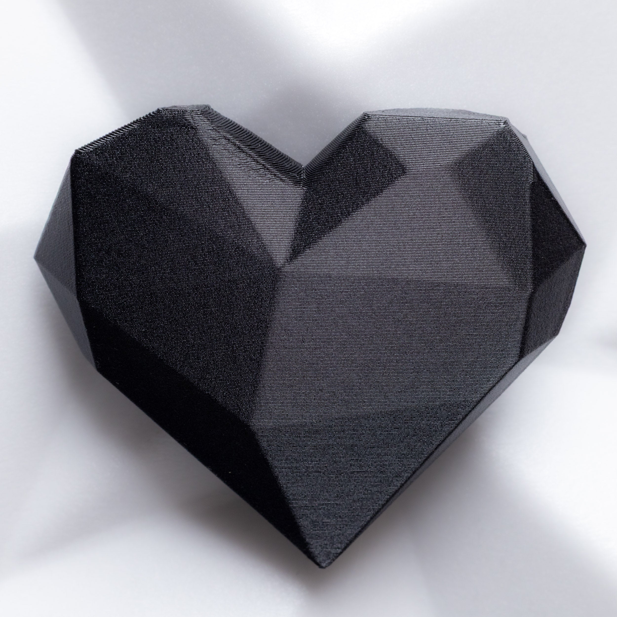 Black geometric heart-shaped brooch on a white background